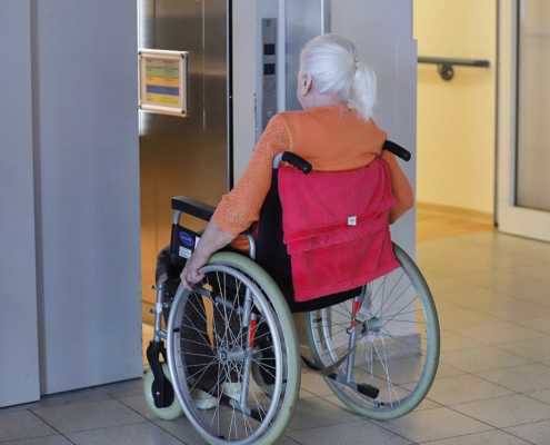 Frau sitzt in einem Rollstuhl im Pflegeheim (Archiv)