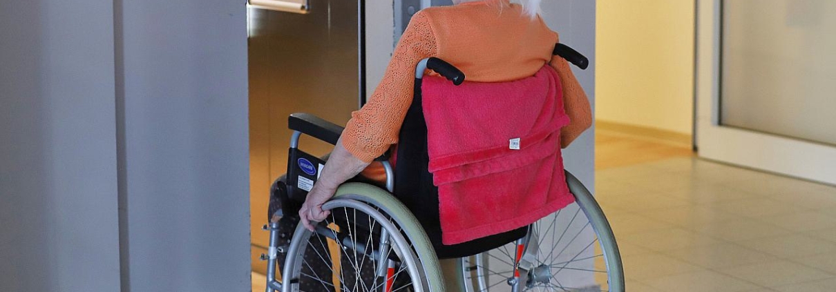 Frau sitzt in einem Rollstuhl im Pflegeheim (Archiv)